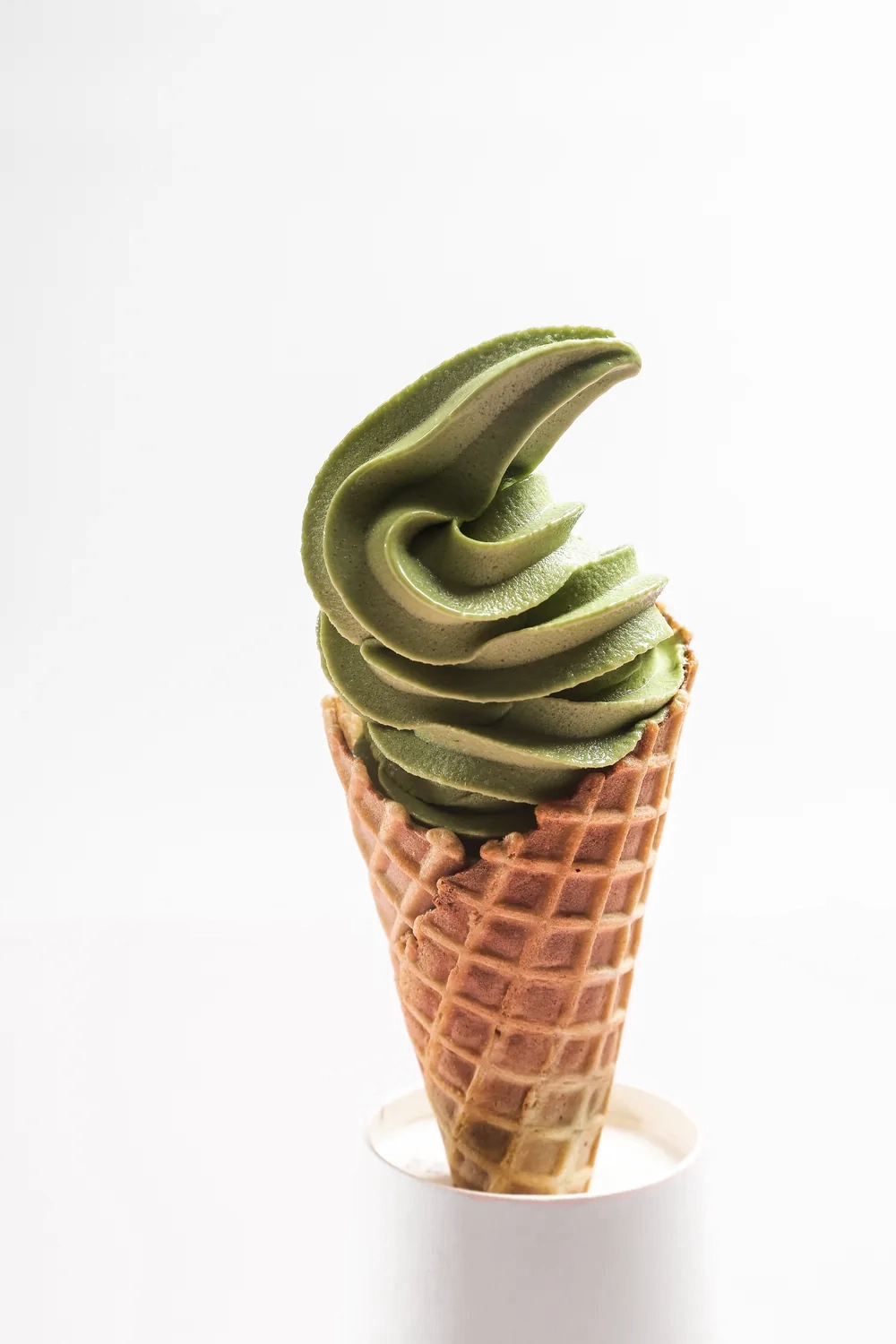 A matcha soft serve in a waffle cone.
