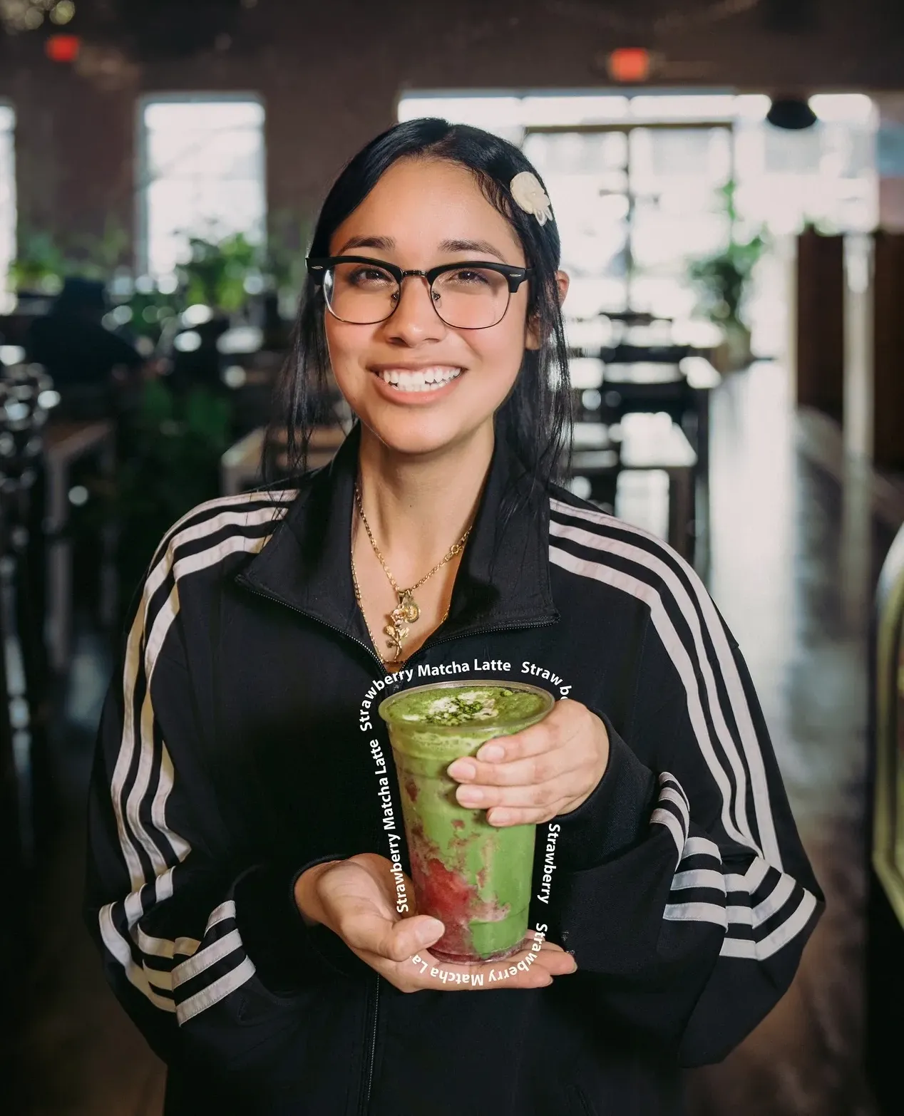 A staff member holding a matcha latte at the counter.